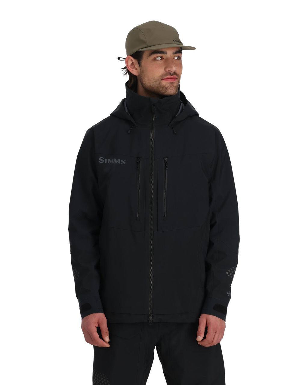 Man i svart Simms Pro Dry GORE-TEX-fiskejacka och khakikeps, redo för fiskeresa, mot enkel vit bakgrund.