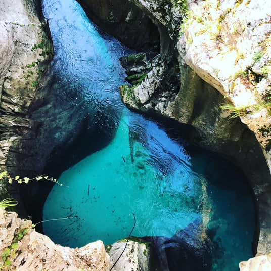 Flygfoto över en smal, stenig kanjon med klart turkost vatten-perfekt plats för sportfiske och minnesvärda fiskeresor.