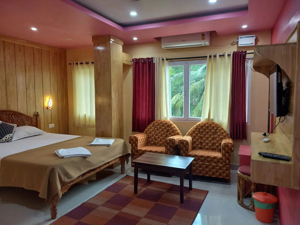 Hotellrum för fiskeresa med dubbelsäng, två fåtöljer, bord, vägg-TV, fönster mot palmer och träpanel för avkopplande atmosfär.