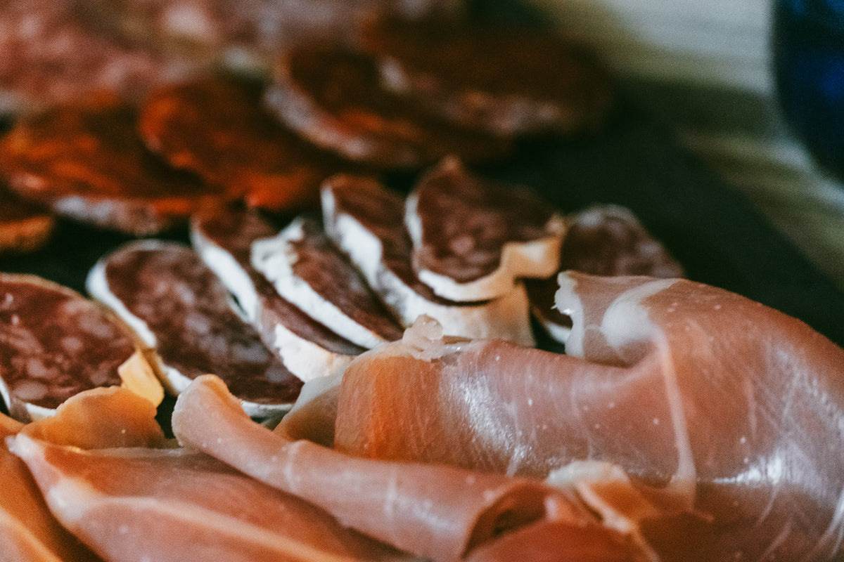 Närbild på charkuterier med prosciutto och salami, upplagt för delning efter fiskeresa eller med sportfiskevänner.