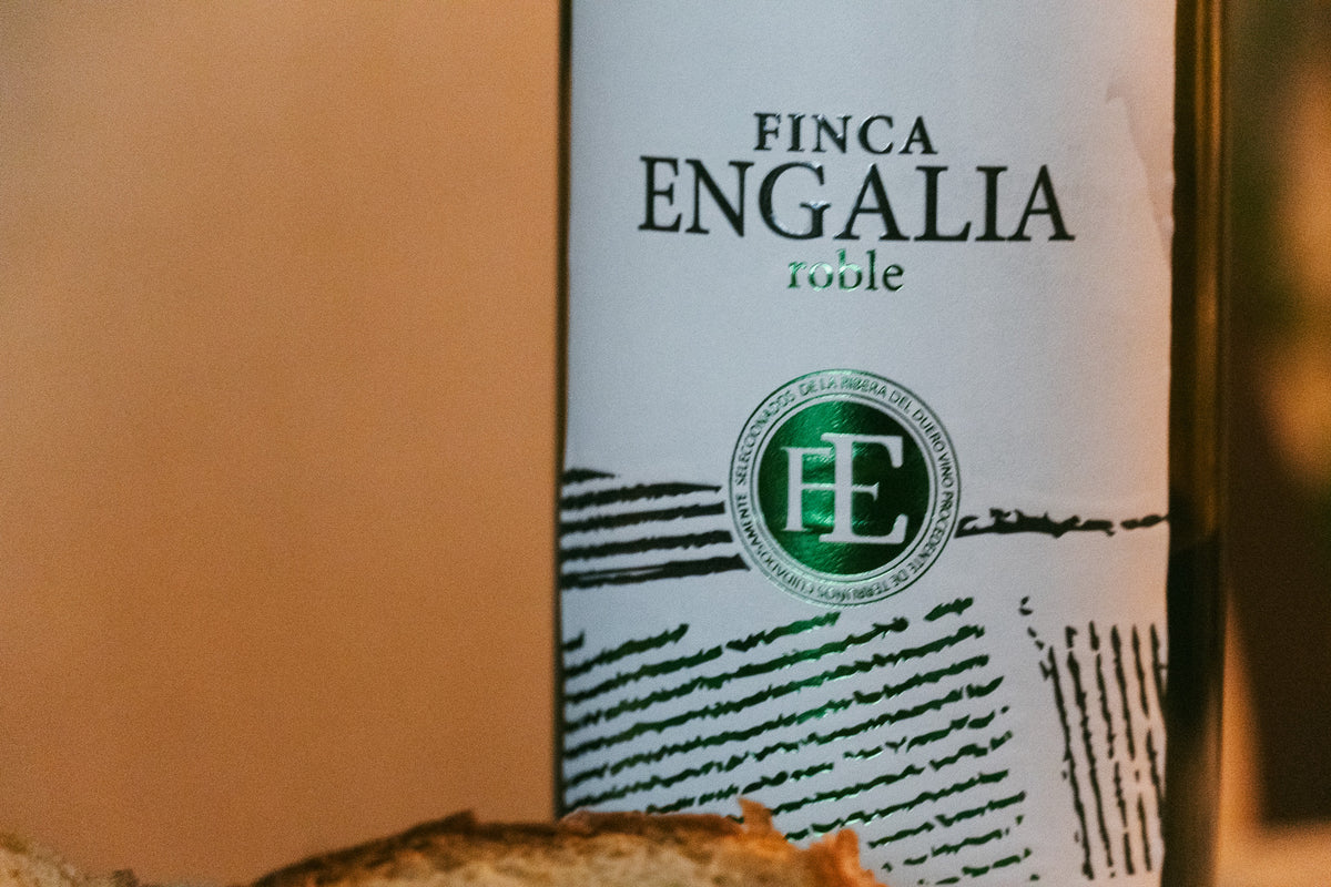 Närbild på Finca Engalia roble vinflaska med grönt FE-emblem, svarta linjer och bröd - idealiskt för sportfiskarresa.