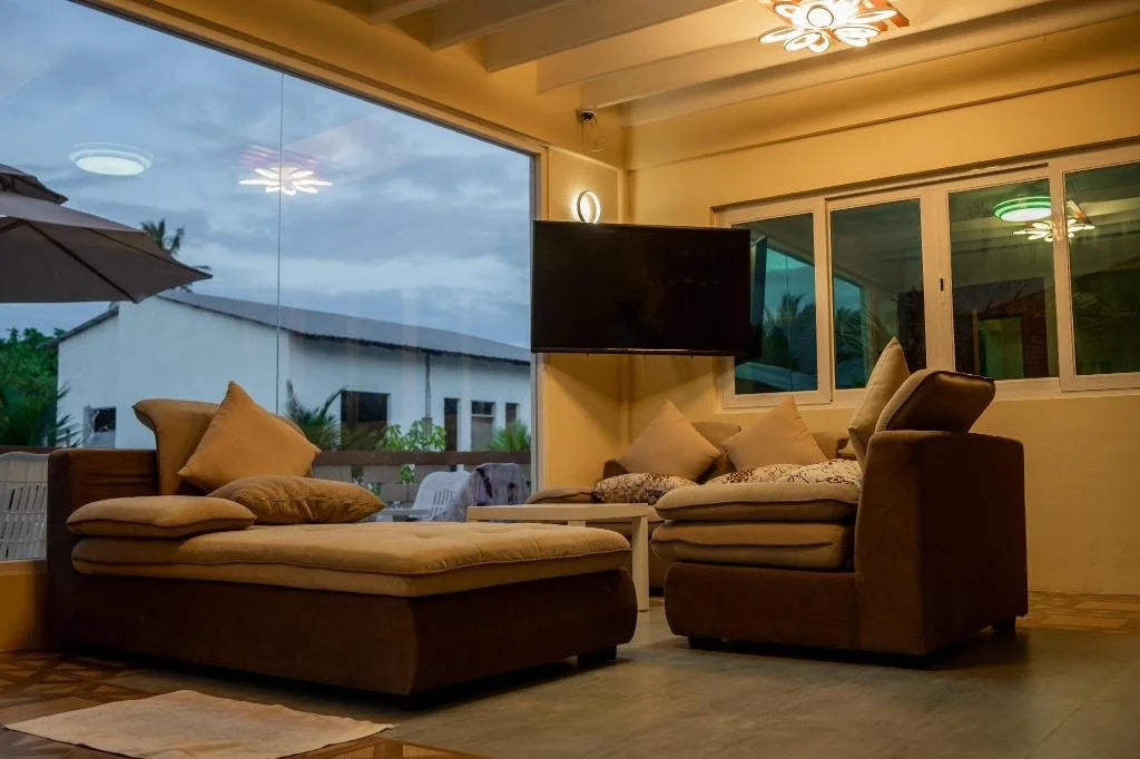 Modernt vardagsrum med stora fönster, bruna soffor, väggmonterad TV och uteplats - perfekt för avkoppling efter fiskeresa.