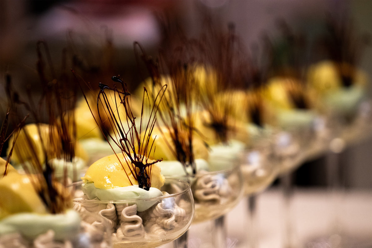 Eleganta dessertglas med mousse, gul kula och grön garnering - perfekt uppläggning för sportfiskarresans middag.