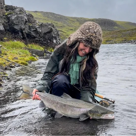 Laxfiske på Island med tjej som håller i en lax tagen på fluga