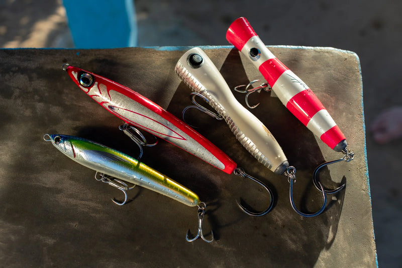 Fyra färgglada fiskedrag med metallkrokar på rad, i rött, vitt, grönt, gult och silver-perfekta för nästa fiskeresa.