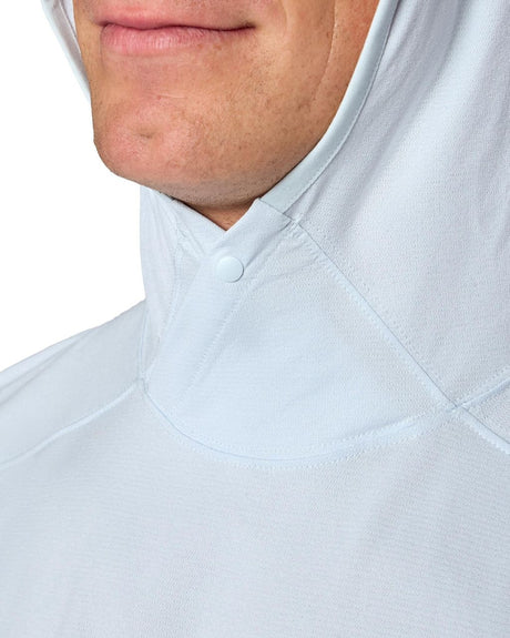 Närbild av fiskare i ljusblå Simms SolarFlex Hoody, huvan uppdragen för solskydd under fiskeäventyr.