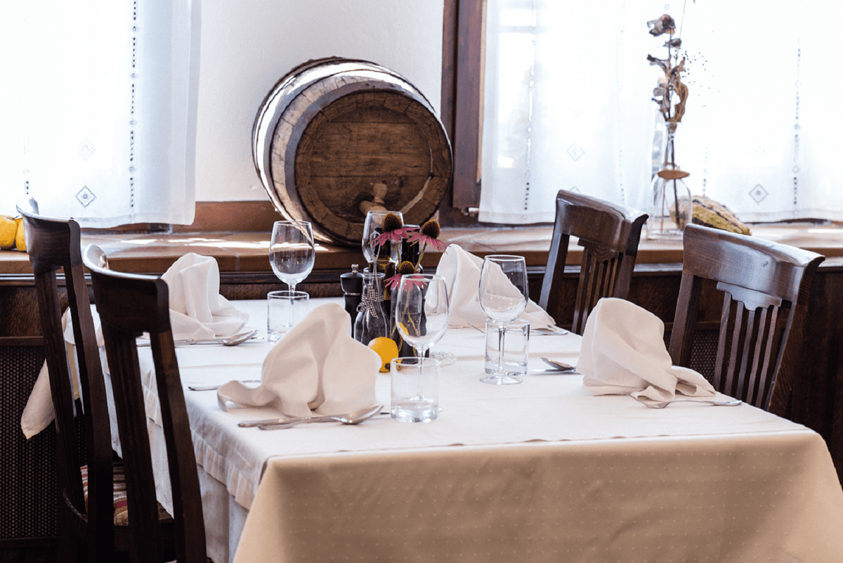 Vackert dukat bord med vita dukar, vinglas och trästolar. Tunna och blommor vid fönstret - perfekt efter fiskeresa.